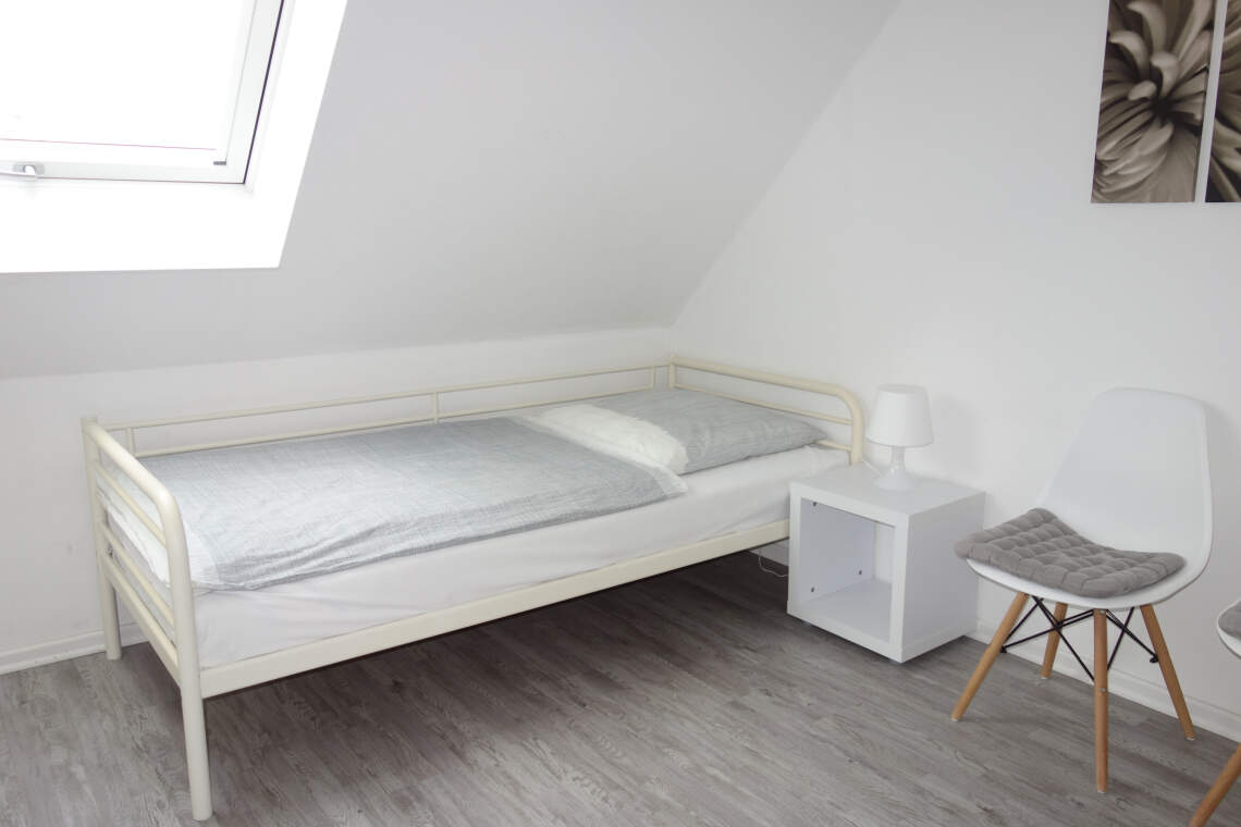 Oberes Schlafzimmer mit Fenster, Einzelbett und Nachttisch